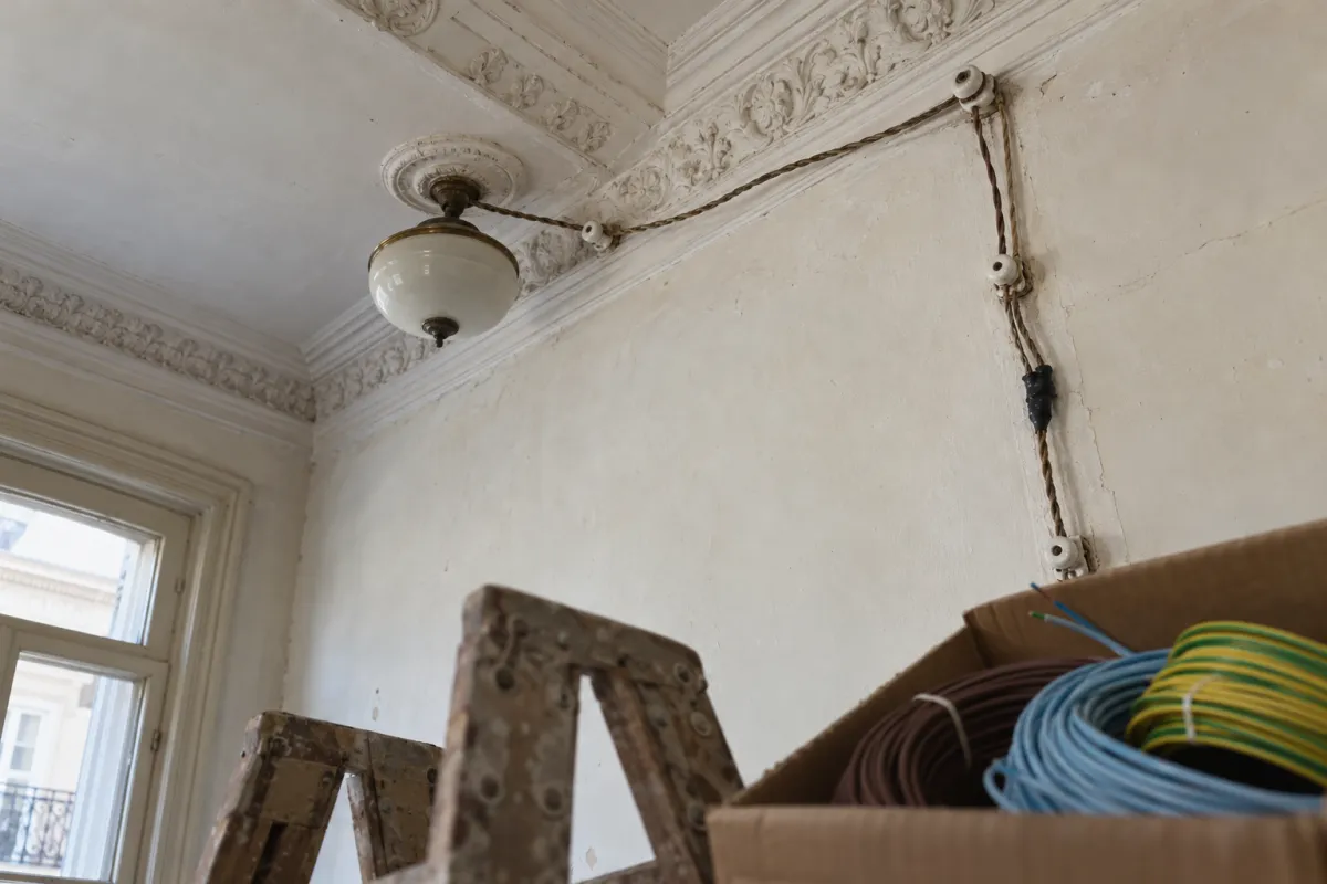 Instalación antigua a la vista con cables de tela sobre aisladores de porcelana en el techo de una casa vieja